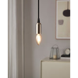 Amber LED candle bulb, E14 fitting, glowing warm white in a brushed metal pendant light fitting above a light grey room with framed wall art.