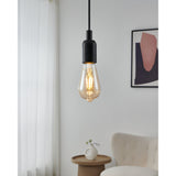 Amber LED vintage bulb, ST64 teardrop shape with E27 brass-coloured screw cap, shown lit in a black pendant fitting above a light, neutral-toned living room.