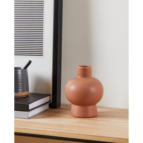 Anjabe Ceramic Vase 15.5cm in terracotta, a round-bodied vase with flared foot and short neck, styled on a wooden shelf beside books and a black-framed print.