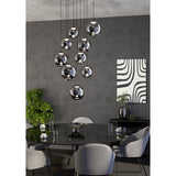 Anorias 9 Light Pendant with smoked glass globes of varying sizes cascading at different heights, black nickel canopy, shown above a dining table.