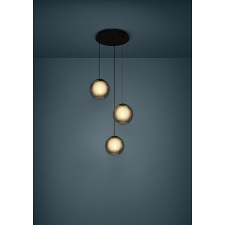 Arangona Glass 3 Light Pendant in black, round ceiling canopy with three staggered grey glass globes, shown illuminated against a dark teal wall.