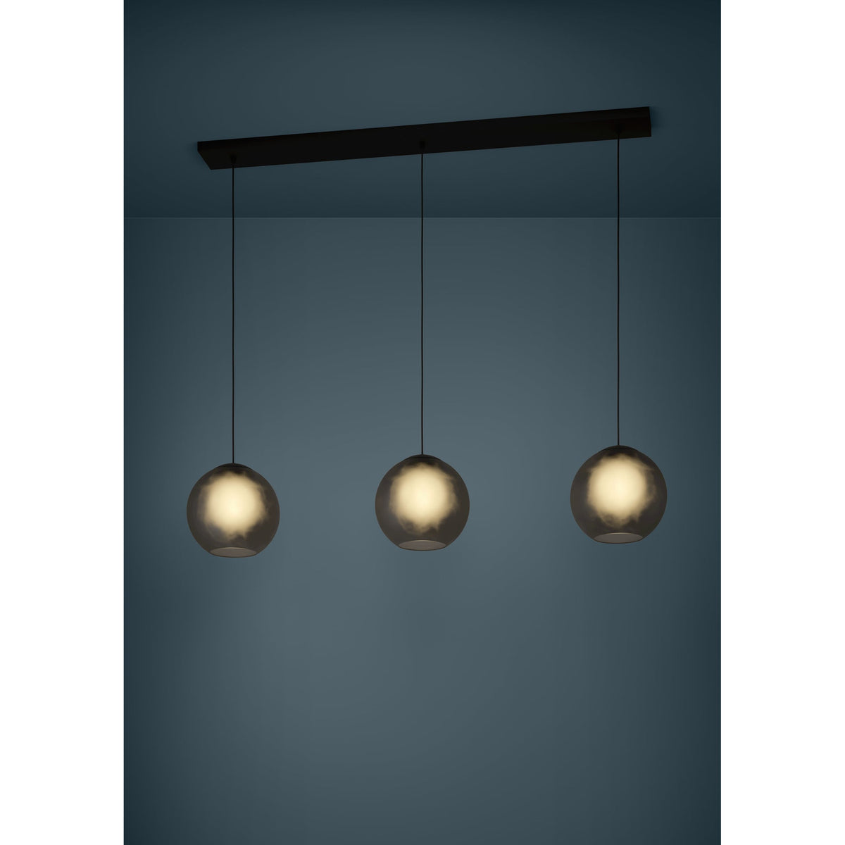 Arangona Glass Linear Pendant Light in black, three smoked grey globe shades on black cords suspended from a long black steel ceiling bar, shown illuminated against a dark blue background.