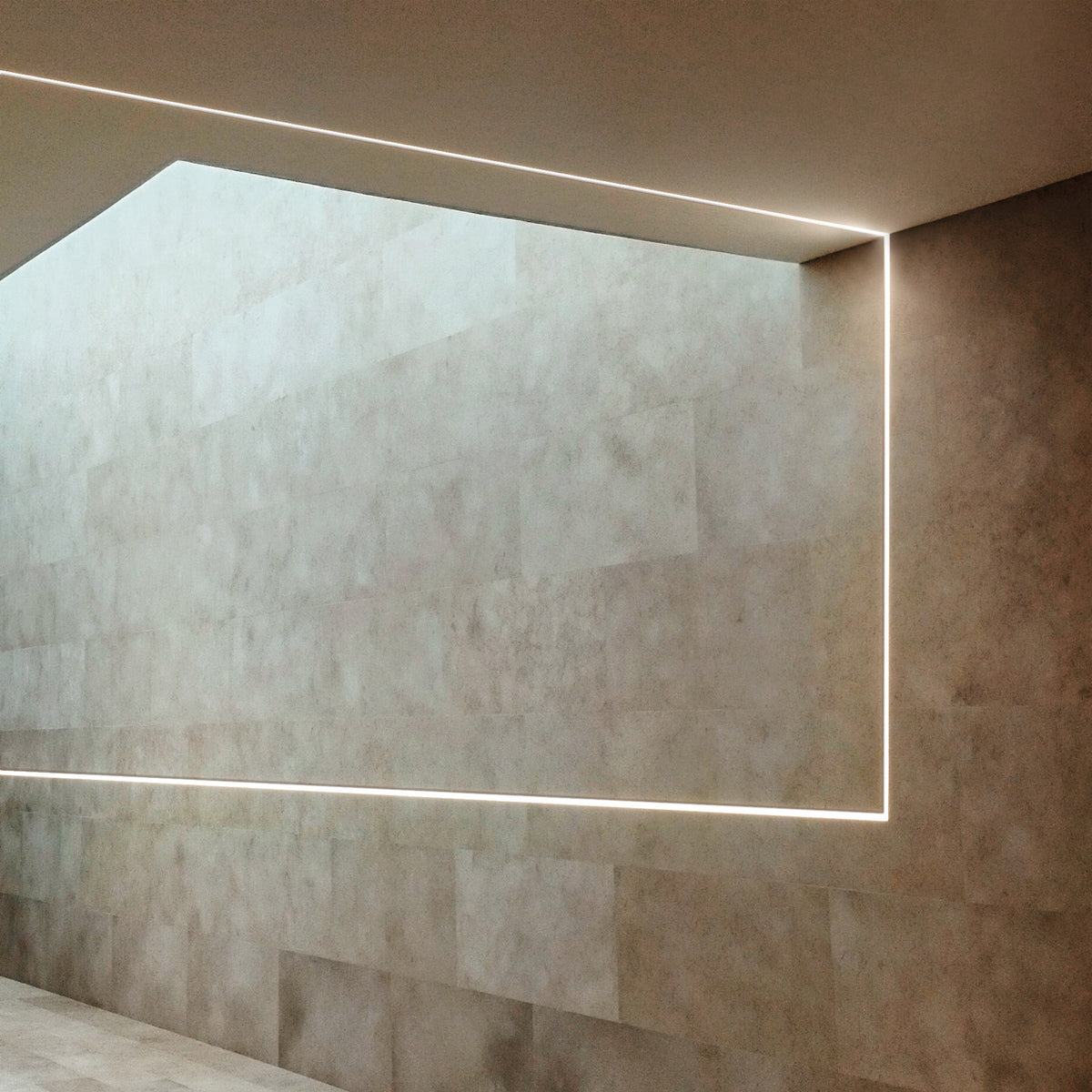 Arcus 2m plaster-in LED profile forming an illuminated recessed line where a stone-tiled wall meets the ceiling in a corridor setting.