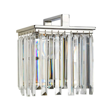 The Aries Wall Light - Polished Nickel is a remarkable square fixture that boasts multiple tiers of cut glass crystals. These prisms magnificently reflect and refract light, creating a dazzling rainbow effect that brings a modern touch of elegance to any space.