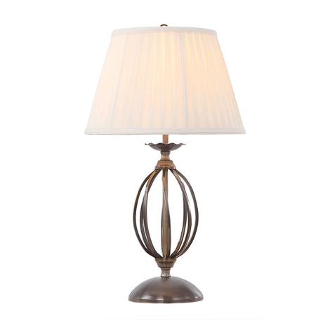 The Artisan Table Lamp - Aged Brass boasts an ornate spherical base design and is complemented by a pleated white shade, producing a warm glow when illuminated.