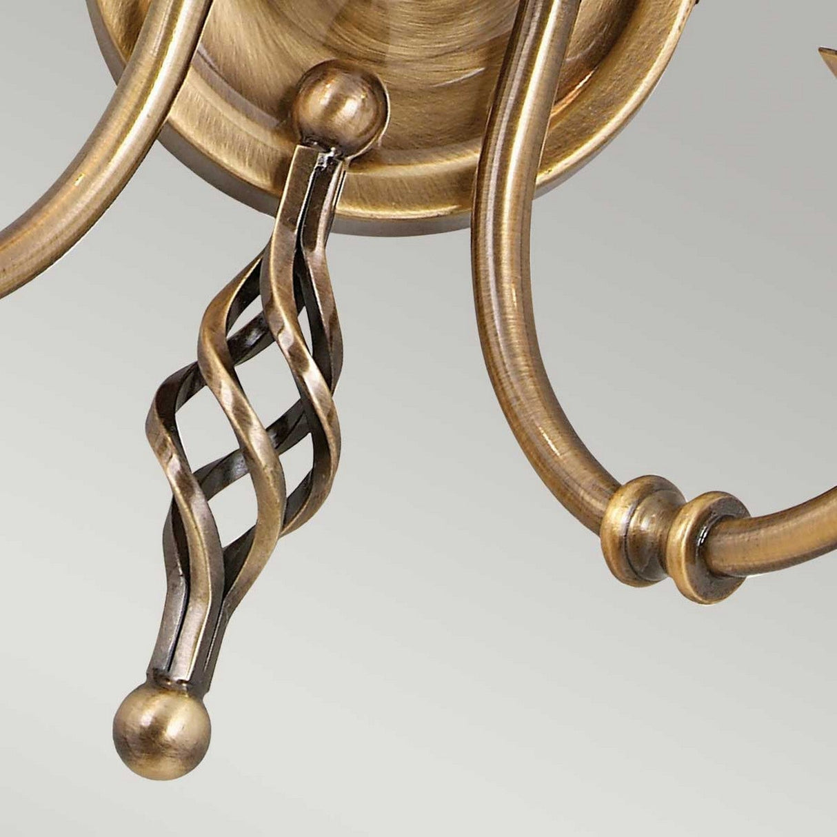 Close-up of the Artisan 2 Light Wall Light in aged brass, featuring a swirling, twisted design on its arm. This fixture represents artisan craftsmanship and elegant detailing, with its polished finish displayed against a neutral background.