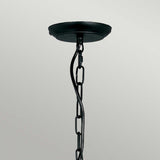 A twisted metal chain and black ceiling canopy suspend the Artisan 5 Light Chandelier - Black, showcasing hand-formed scrolls against a light gray background.