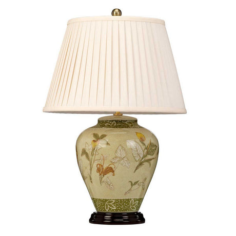 The Arum Table Lamp - Aged Brass showcases a floral design reminiscent of Chinese porcelain, set on a green ceramic base and complemented by a pleated cream-colored lampshade, elegantly displayed against a white background.