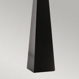 A tall, sleek black obelisk stands against a gradient gray background, highlighting its smooth and glossy finish—a testament to contemporary design reminiscent of the Ascent Table Lamp - Black/White.