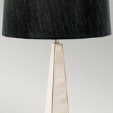 Presenting the Ascent Table Lamp with Black Shade - Polished Nickel, which boasts a polished nickel finish and a modern, triangular metallic base. Its textured black shade adds a touch of contemporary style, beautifully enhancing any neutral gray setting.
