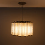 Ashford Acrylic 20 Light Chandelier, a scalloped circle of tall ribbed clear acrylic cylinders with brass rims, suspended from a round ceiling plate, glowing warm against a dark background.