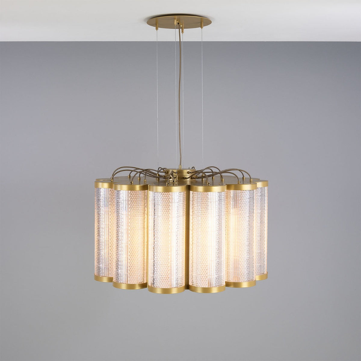 Ashford Acrylic 20 Light Chandelier, a scalloped ring of tall textured acrylic cylinders with brass finish rims, suspended from a brass ceiling plate against a plain grey background.