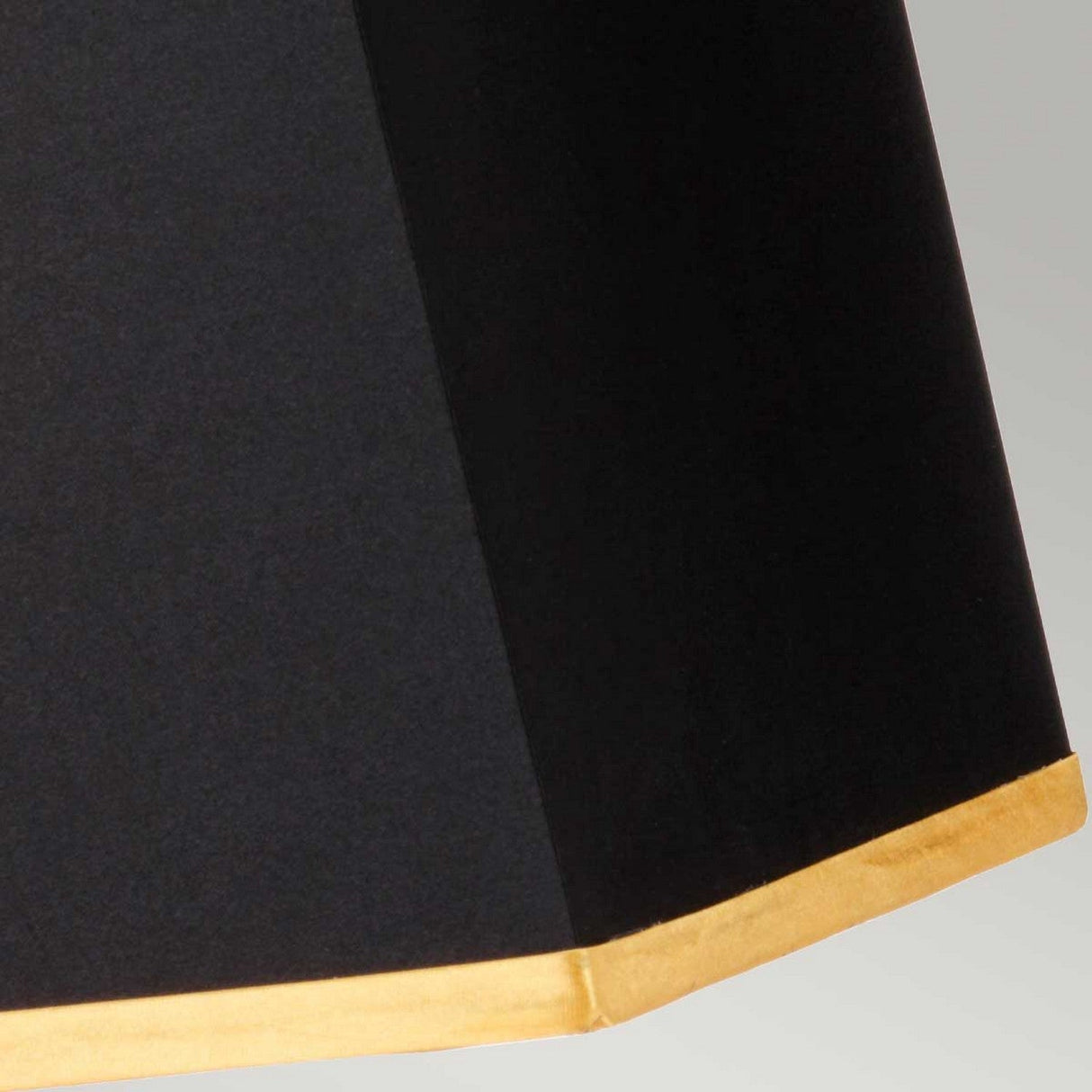 Close-up of the Atlas Table Lamp - Brushed Brass, featuring a black lampshade with a subtle texture and gold trim at the bottom edge, sitting atop its elegant marble base. The background is a neutral light gray.