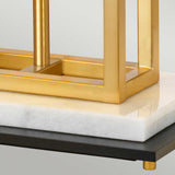 A detailed view of the Atlas Table Lamp - Brushed Brass showcases its sleek rectangular frame beautifully set on a white marble base. The marble piece is elegantly positioned on a black surface supported by petite gold feet, adding depth and sophistication to the design.