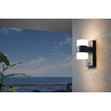 Atollari LED Outdoor Wall Light in anthracite with two white diffusers on a rectangular backplate, mounted on a textured wall beside a sea-view terrace.