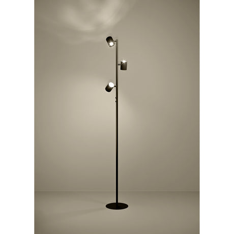Auro LED floor lamp in black steel with three cylindrical spotlight heads at varying heights on a slim pole and round flat base, shown illuminated against a plain neutral background.