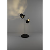 Auro LED Table Lamp in black steel with two adjustable cylindrical spot heads on a slim stem and round disc base, shown lit against a plain grey background.