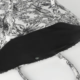 Bachuma Bag in Black showing the open top with plain black interior lining, press-stud closure, and black-and-white jungle toile print fabric and handles.