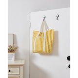 Bachuma Bag in yellow and white stripes with cream webbing handles, hanging from black hooks on a white door in a bedroom setting.