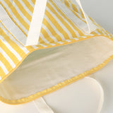 Close-up of the Bachuma Bag, a yellow and white striped fabric tote, showing the cream interior lining, zip trim, and webbing handles.