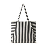 Bachuma Striped Bag in black and cream woven fabric, with vertical front stripes, horizontal side panels, two shoulder straps, and a snap-top closure, shown on a plain white background.