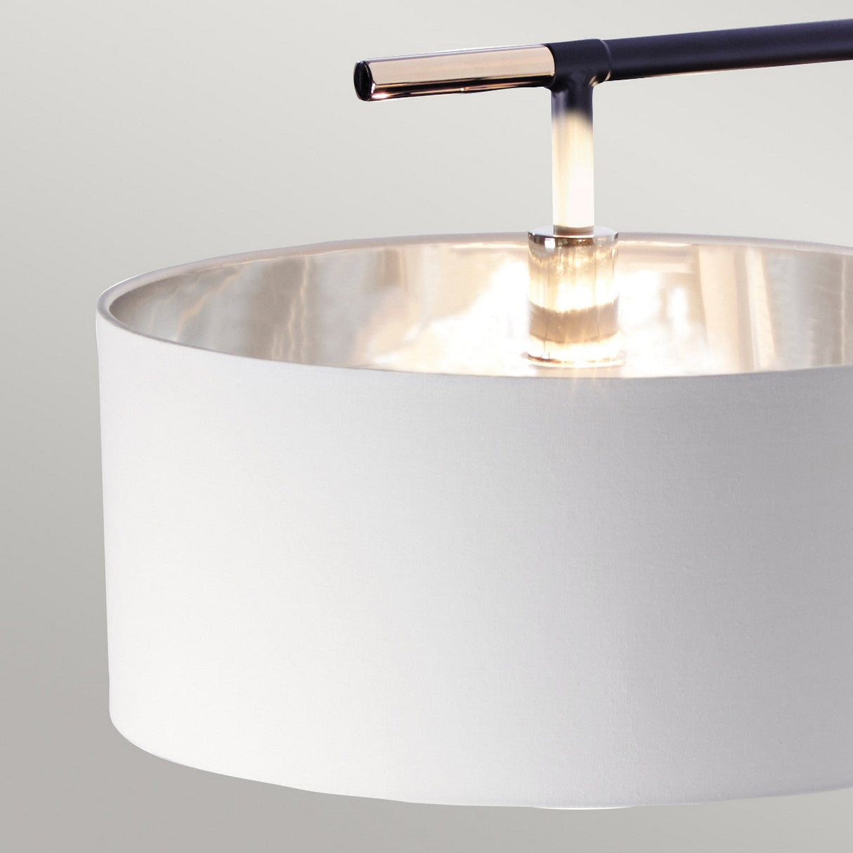 Close-up of the energy-efficient Balance Floor Lamp featuring a black and polished nickel finish with a white cylindrical shade and metallic rod. The lamp emits a warm glow, complementing the modern decor against a soft grey background.