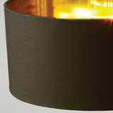 Close-up of the Balance Table Lamp - Black/Polished Brass, highlighting its dark lampshade with a warm, glowing light at the top. The lamp's textured fabric exterior and polished brass accents perfectly blend modern design with cozy elegance, creating an inviting atmosphere.