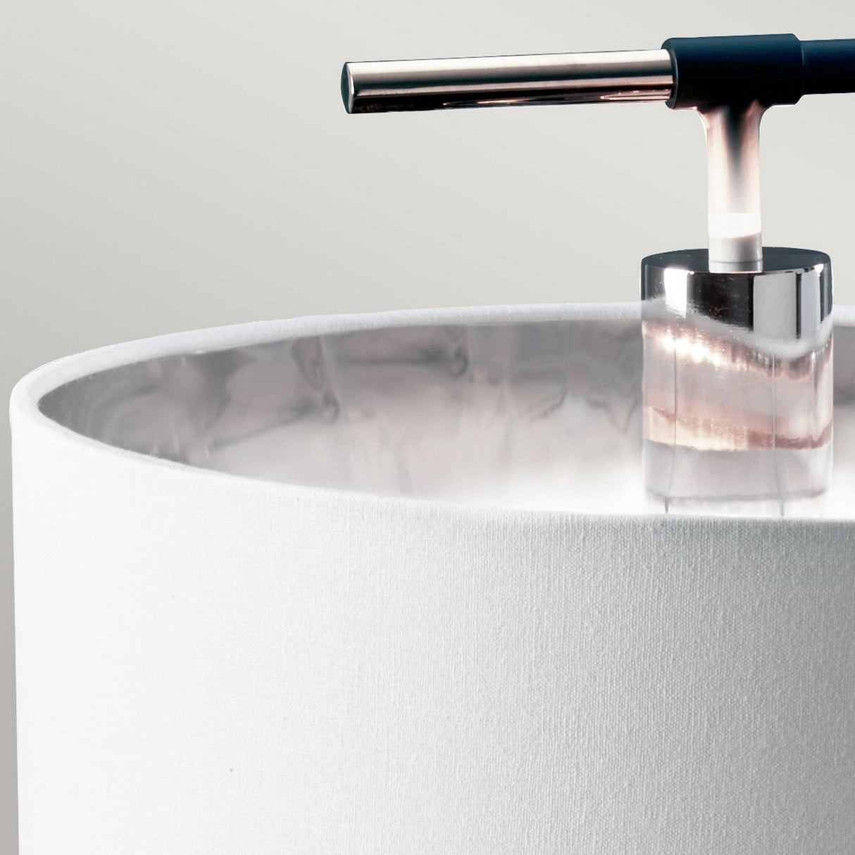 Close-up of the Balance Table Lamp - Black/Polished Nickel, showcasing a cylindrical white fabric shade. This lamp features a contemporary design with its chrome stand and horizontal black handle, enhanced by accents of polished nickel, all set against a neutral background.