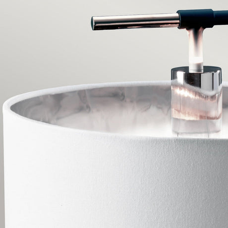 Close-up of the Balance Table Lamp - Black/Polished Nickel, showcasing a cylindrical white fabric shade. This lamp features a contemporary design with its chrome stand and horizontal black handle, enhanced by accents of polished nickel, all set against a neutral background.