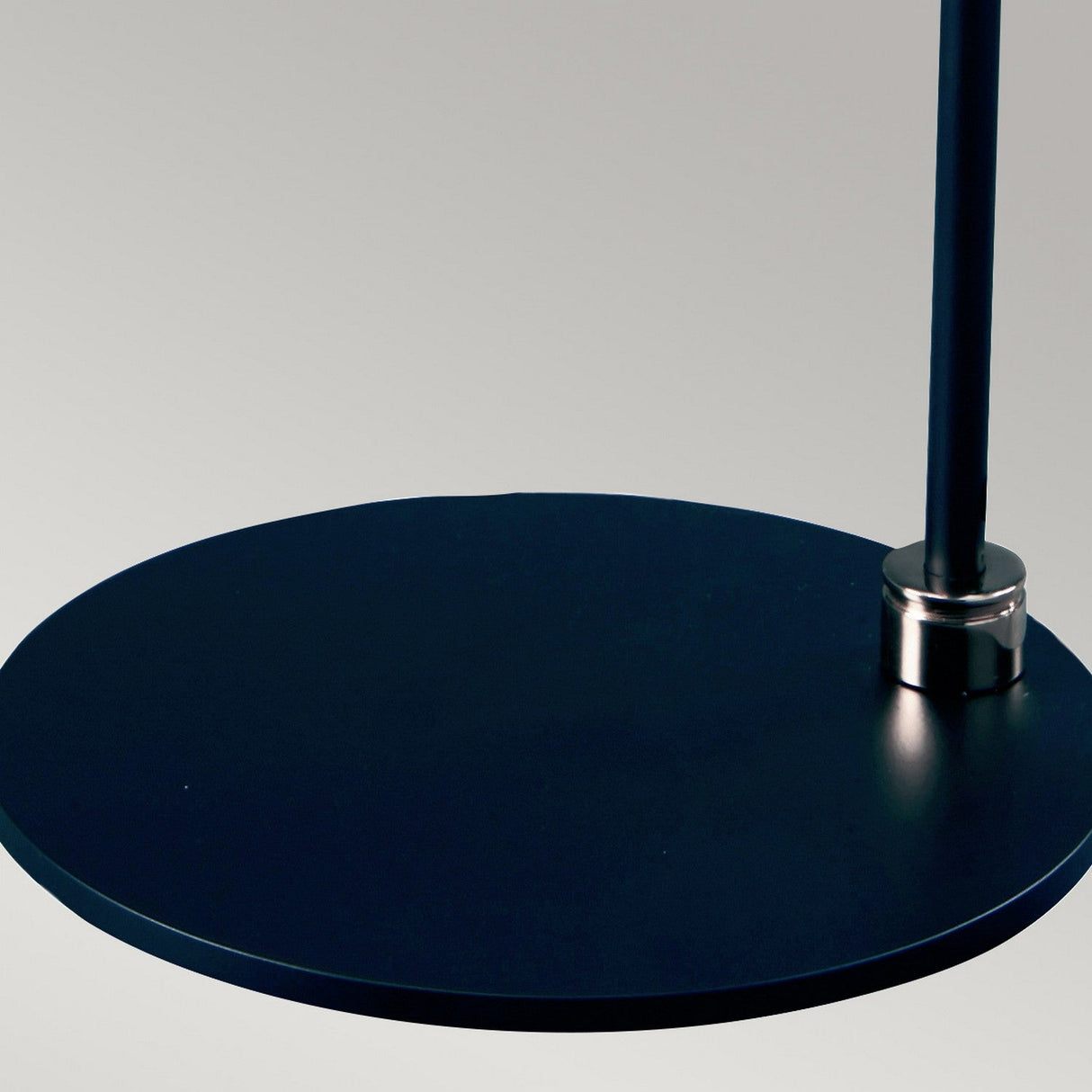 Close-up of the Balance Table Lamp - Black/Polished Nickel, featuring a sleek, modern circular metal base with a vertical rod, set against a light gray background. The design showcases a minimalist and contemporary aesthetic.