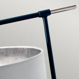 Close-up of the Balance Table Lamp, showcasing its minimalist design with a sleek handle that highlights its contemporary aesthetic. The black metal frame and white lampshade blend seamlessly against the soft gray background, while hints of polished nickel add a touch of subtle sophistication.