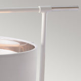 Close-up of the Balance 1 Light Table Lamp, showcasing its white fabric shade and sleek, minimalist design. It features a cylindrical frame and a horizontal metal arm in polished nickel, set against a neutral background, perfect for providing ambient light.