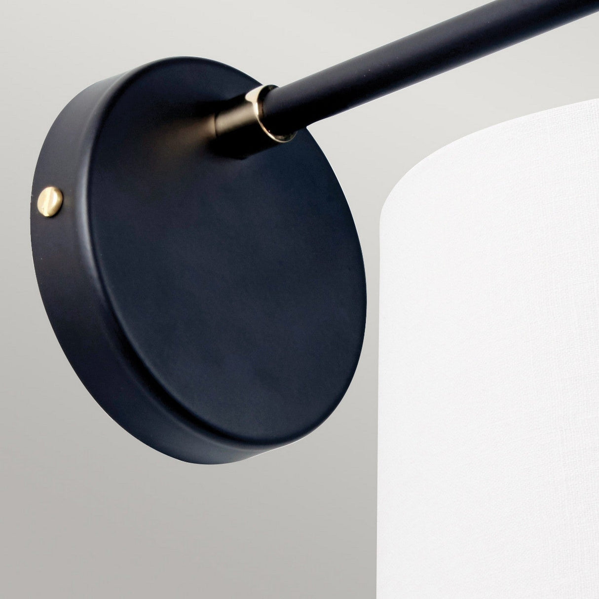 The Balance 1 Light Wall Light in Black and Polished Nickel boasts a sleek design with a circular base and cream-colored cylindrical shade. Its stylish hardware stands out beautifully against a light gray wall, highlighting the lamp's contemporary appeal and energy-efficient features.