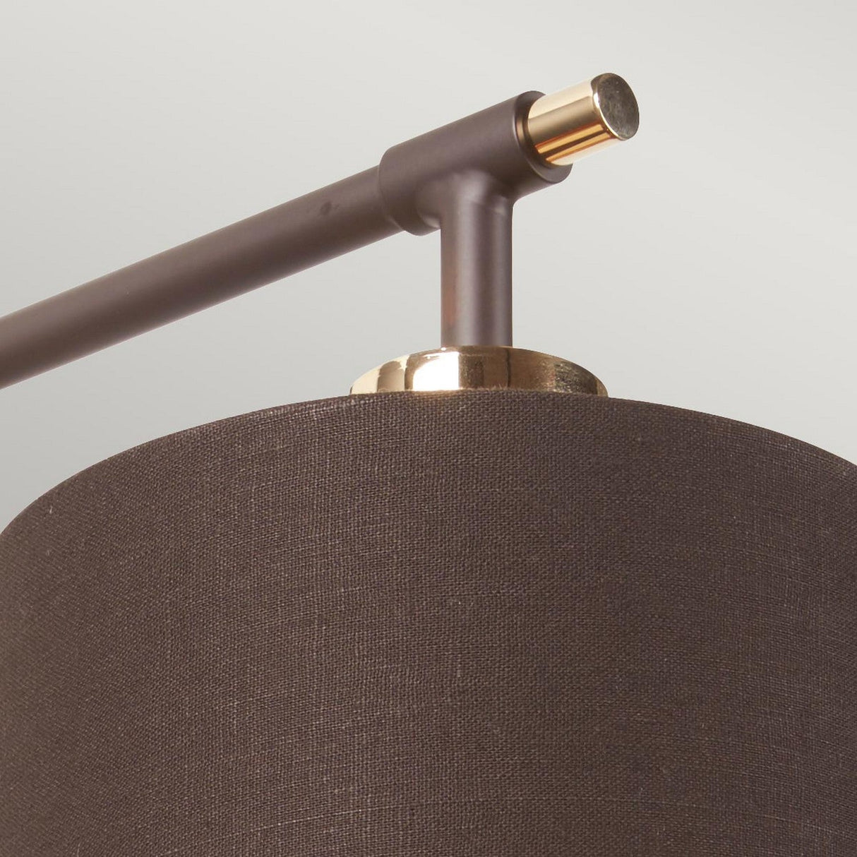 Close-up of the Balance 1 Light Wall Light, showcasing its dark cylindrical fabric shade and polished brass accents in a modern design. The light is not turned on, set against a softly neutral background.