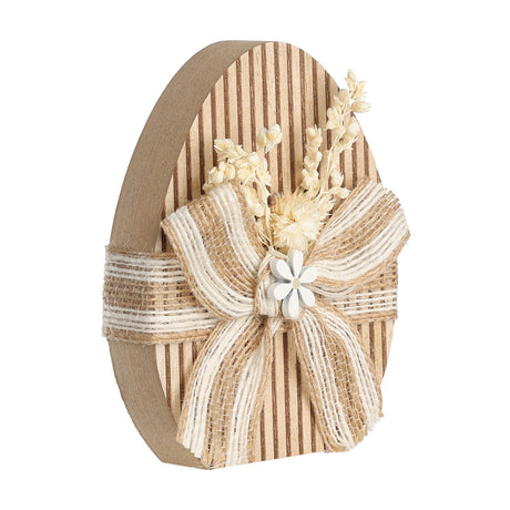 Balmaha Decorative Egg in brown and beige, a ribbed freestanding wooden egg with a jute and white ribbon bow, dried flower sprig, and white flower button, on a plain background.