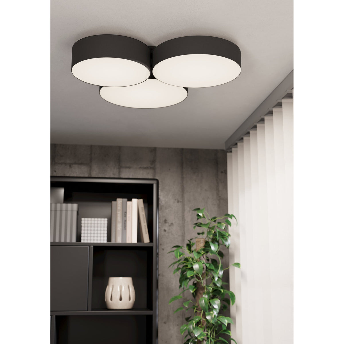 Barbano Smart LED Flush Ceiling Light with three overlapping black fabric drums and white diffusers, mounted on a grey ceiling above a bookshelf and plant.