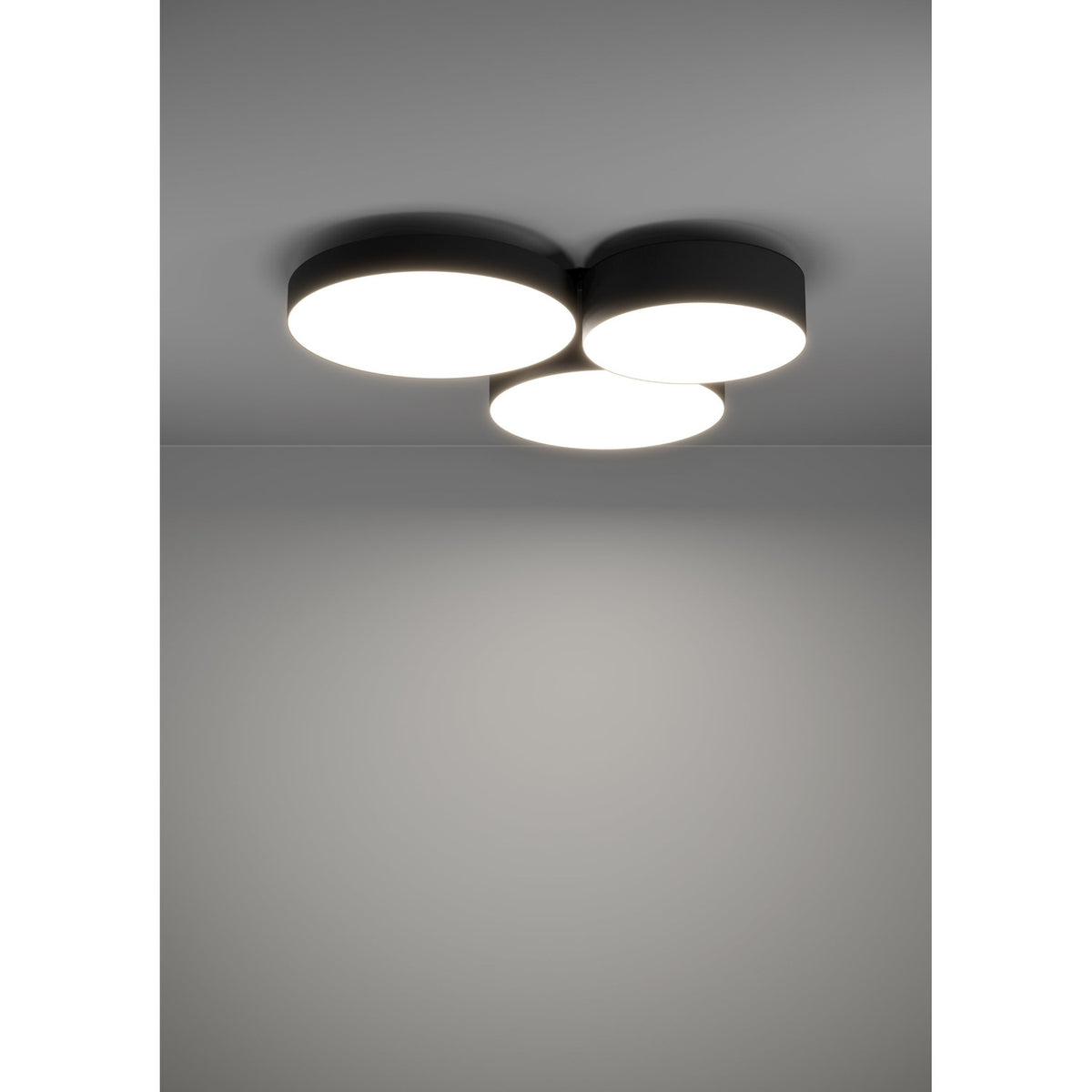 Barbano Smart LED flush ceiling light with three overlapping round drums in black fabric and steel with white diffusers, mounted on a grey ceiling illuminating the room below.