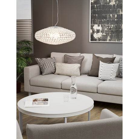 Barbena Clear Glass 3 Light Pendant in chrome, oval shade of round crystal glass pieces hanging above a beige sofa in a living room.