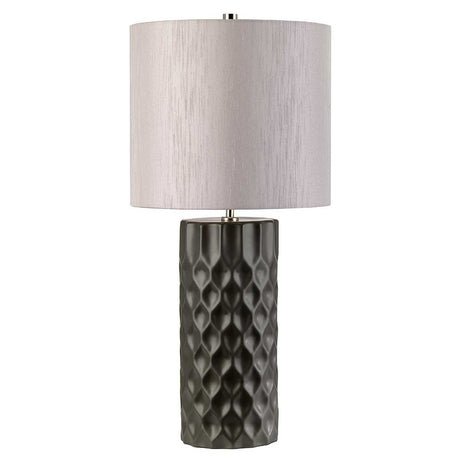 The Barbican 1 Light Table Lamp features a textured dark graphite ceramic base and a light silver fabric drum shade, offering a modern and elegant design that adds sophistication to any room.