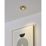 Barranco round recessed downlight in satin nickel with tiltable inner ring, shown on a white ceiling angled to highlight a framed print on the wall below.