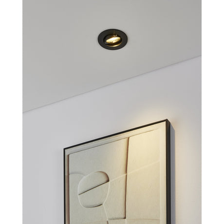 Barranco Downlight 5W 9cm in black, round recessed fitting with tiltable inner ring, shown installed in a white ceiling above a framed textured artwork.