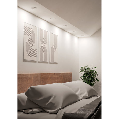 Barranco LED Downlight in white, recessed into a bedroom ceiling above a bed, casting soft light across a wall art triptych and wooden headboard.