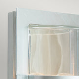 Detailed view of the Basel Outdoor 1 Light Wall Lantern in a sleek, metallic design. This fixture boasts clear glass and minimalist styling with clean lines and a subtle silver finish that enhances its neutral aesthetic.