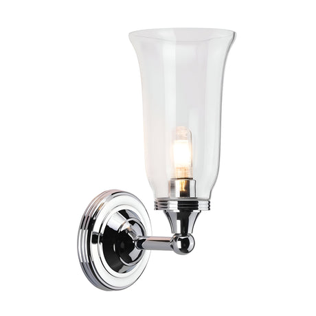 The Austen-2 Wall Light - Polished Chrome is a wall-mounted fixture that features a clear glass shade and an exposed LED G9 bulb. Its sleek design includes a circular base and curved arm, adding a modern touch to any interior decor.