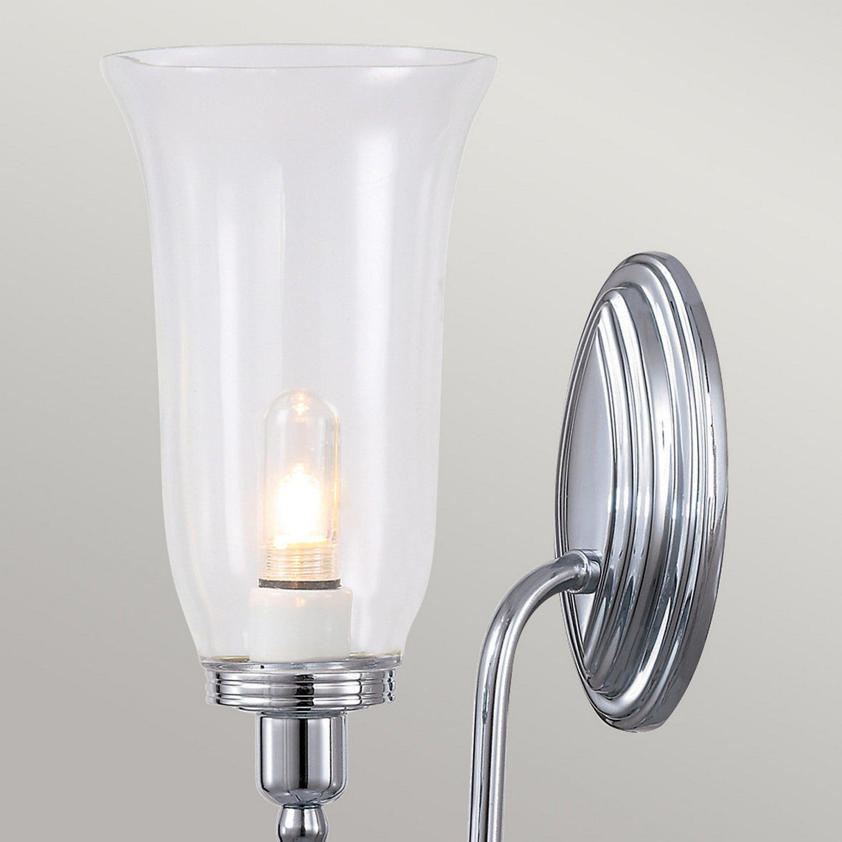 The Blake Wall Light - Polished Chrome includes a clear glass shade that showcases an LED G9 lamp within, set against a light gray background.