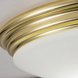 Close-up of the Brompton Flush Light in polished brass, featuring a smooth, frosted white glass cover. The image highlights the contrast between its brass metallic trim and the soft white glass, making it an ideal choice for a bathroom ceiling light.