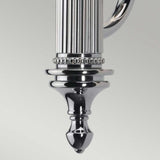 Close-up of the Carroll-2 Wall Light in polished chrome, featuring intricate grooved and beaded patterns that culminate in a pointed finial. The reflective surface gleams against a light gray background, highlighting its role as a contemporary lighting fixture.