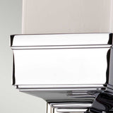 Close-up of the Cambridge Wall Light in polished chrome, showcasing smooth, angular surfaces that reflect surrounding light. Its gleaming chrome finish and clean lines lend a modern, sleek appearance, reminiscent of a sophisticated architectural detail.