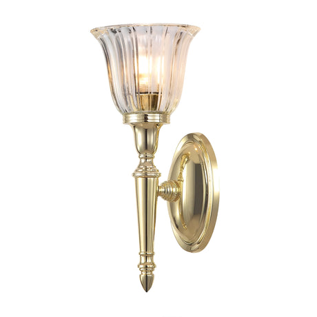 The Dryden-1 Wall Light in polished brass features an ornate design with a fluted glass lampshade. It houses an LED G9 lamp that is partially visible through the translucent shade and is mounted on a round wall plate.