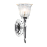The Dryden-1 Wall Light in polished chrome showcases a fluted glass shade illuminated by a soft, glowing LED G9 lamp. Its modern design blends a reflective base with a vertical stem, making it an ideal addition to both contemporary and traditional interiors.
